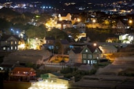Evening view of the farm community with smart lighting and eco-friendly homes nestled among trees.