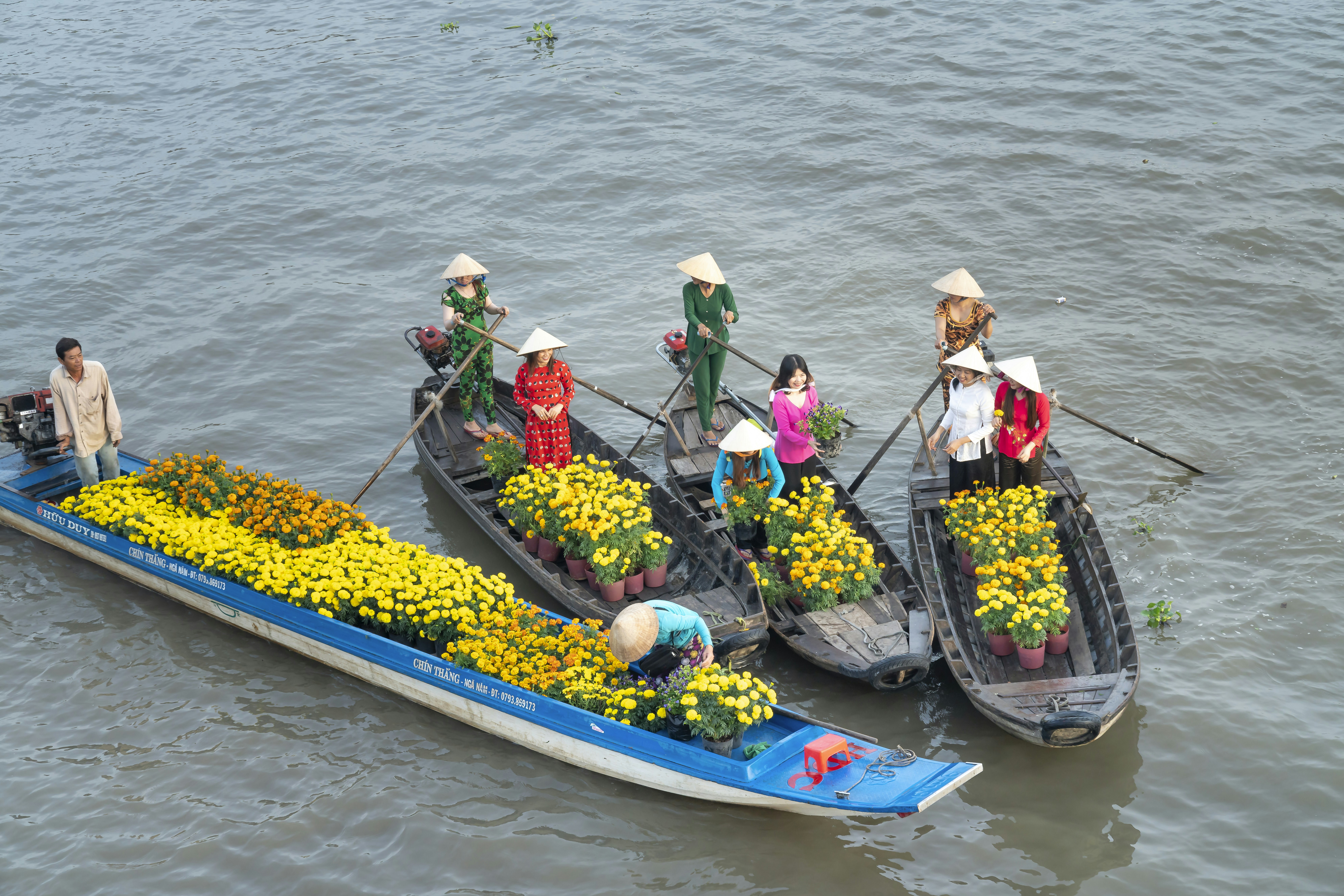 a group of people riding on top of a boat filled with flowers