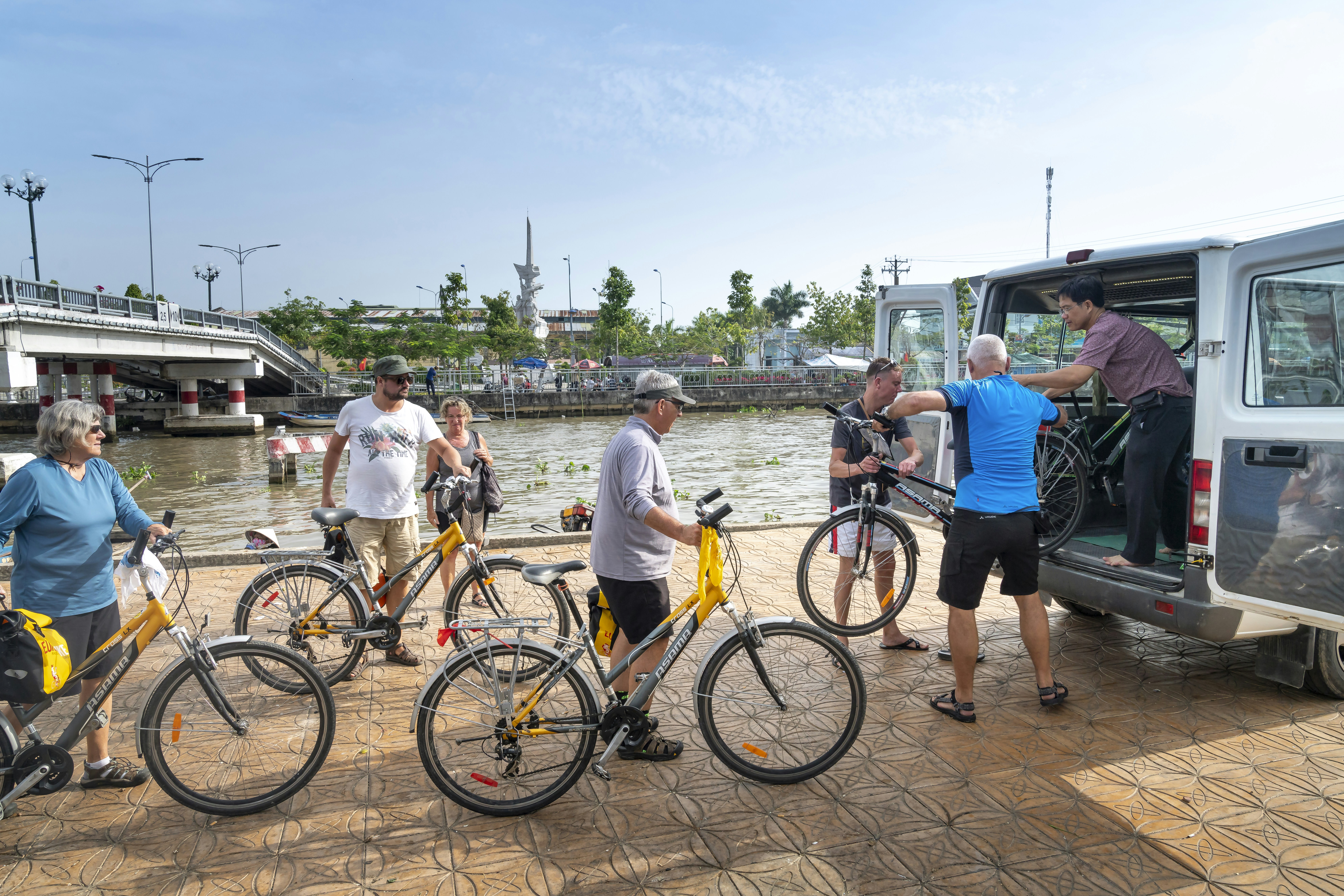 a group of people standing next to bikes near a body of water
