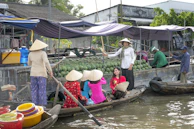 Traditional Vietnamese women in conical hats rowing small boats through the floating markets of the Mekong Delta.