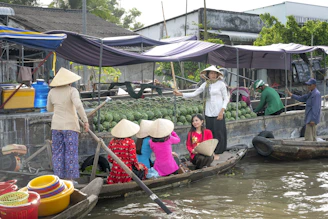 Traditional Vietnamese women in conical hats rowing small boats through the floating markets of the Mekong Delta.