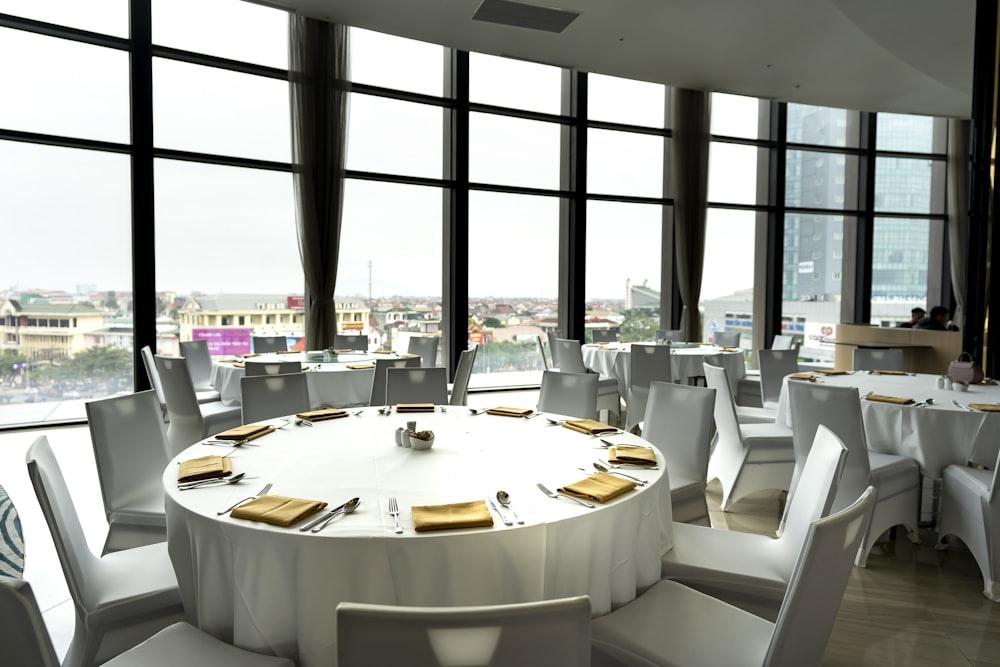 a round table with white linens and gold place settings