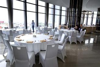 a room filled with lots of white tables and chairs