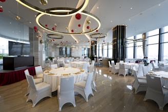 a banquet room with white tables and white chairs
