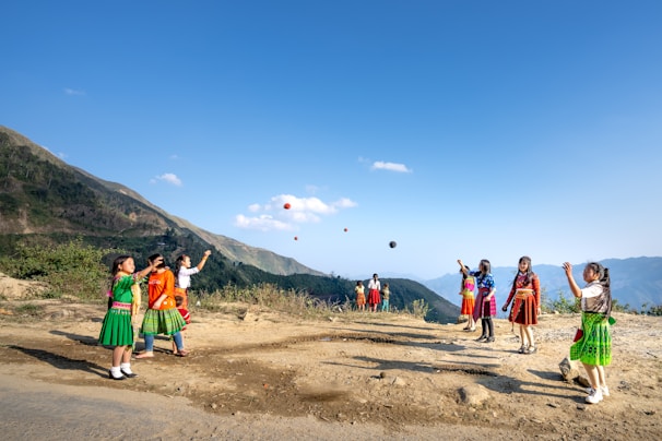 Group of children laughing together while practicing juggling with colorful balls.