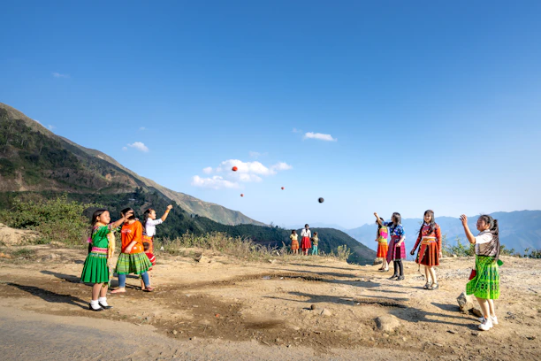 A group of travelers playing traditional rural sports together in a scenic mountain village.