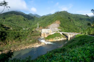Hydroelectric dam with water flowing powerfully, surrounded by lush green landscape.