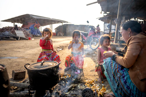 Travelers sharing a traditional meal with a tribal family around a fire.