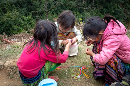 a group of young girls sitting on top of a grass covered field