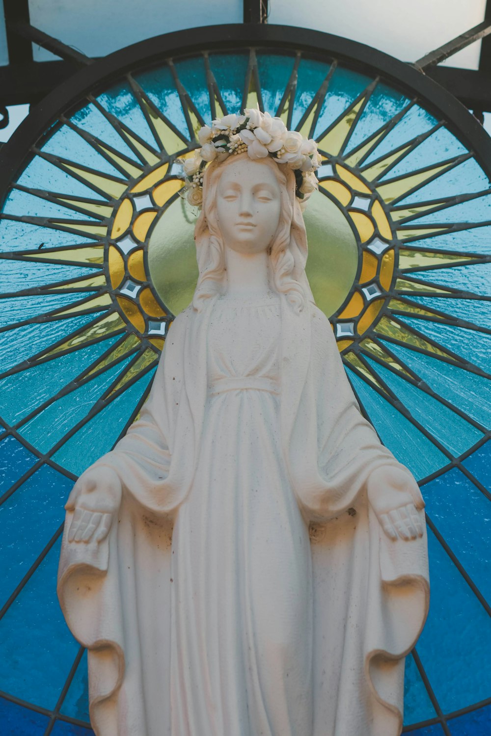 a statue of a woman in front of a stained glass window