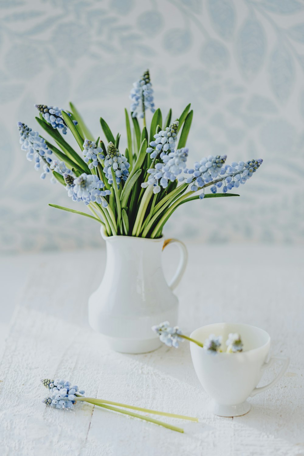 a white vase filled with blue flowers on top of a table