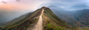 Sunset over a winding mountain trail with a lone traveler in a vibrant jacket