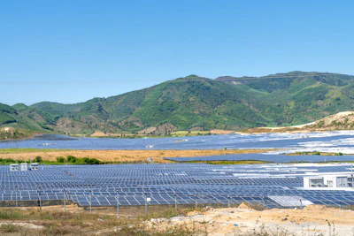 Close-up of solar panels capturing sunlight with green hills in the background