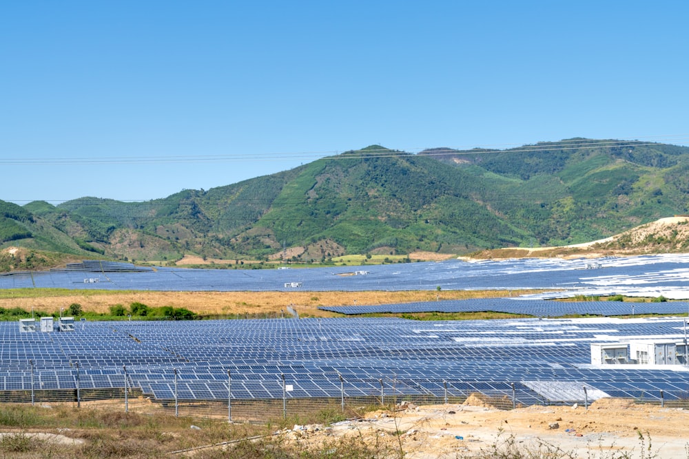 a field of solar panels with mountains in the background