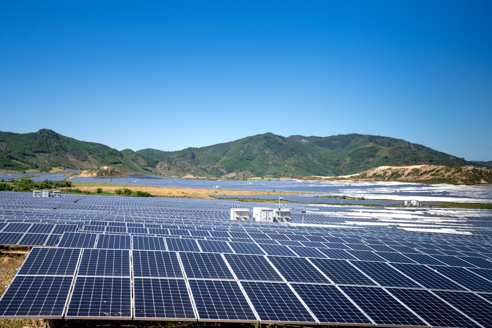 a large field of solar panels with mountains in the background