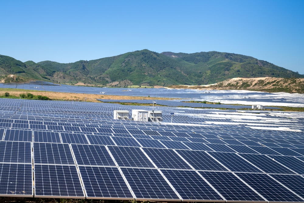 a field of solar panels with mountains in the background