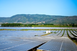 A large-scale solar power plant with rows of panels stretching towards the horizon on a sunny day.