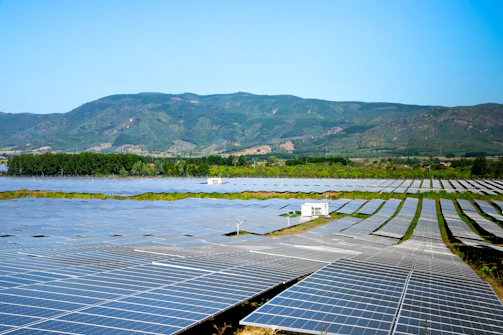 A panoramic view of a large-scale solar energy farm under clear blue skies in Ghana.