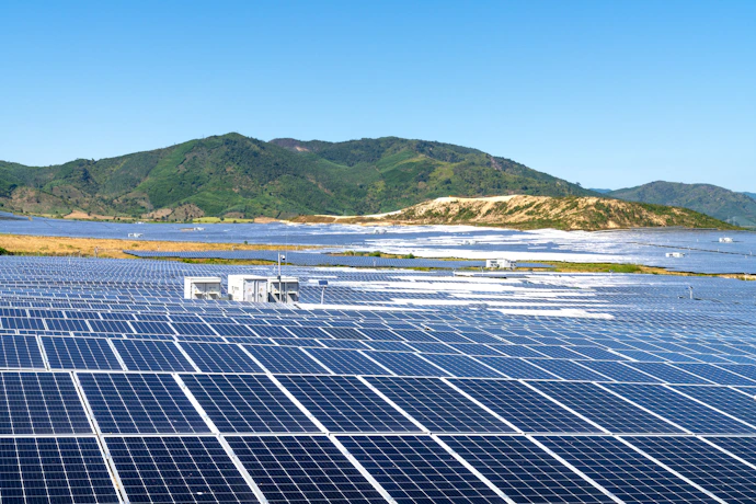 a photo of a solar farm with mountains in the background