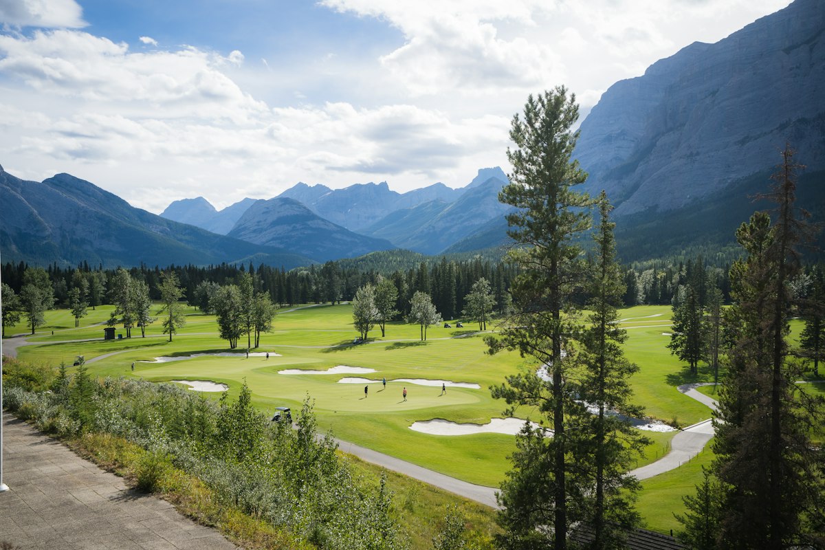 Golf course fairway with mountain views and pine trees in the background
