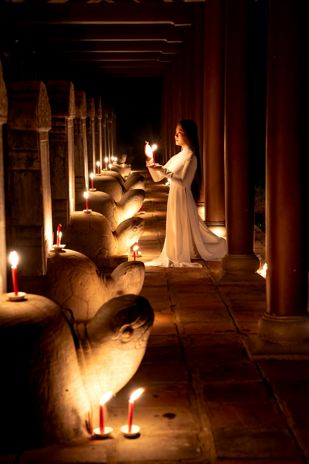 a woman in a long white dress holding a lit candle