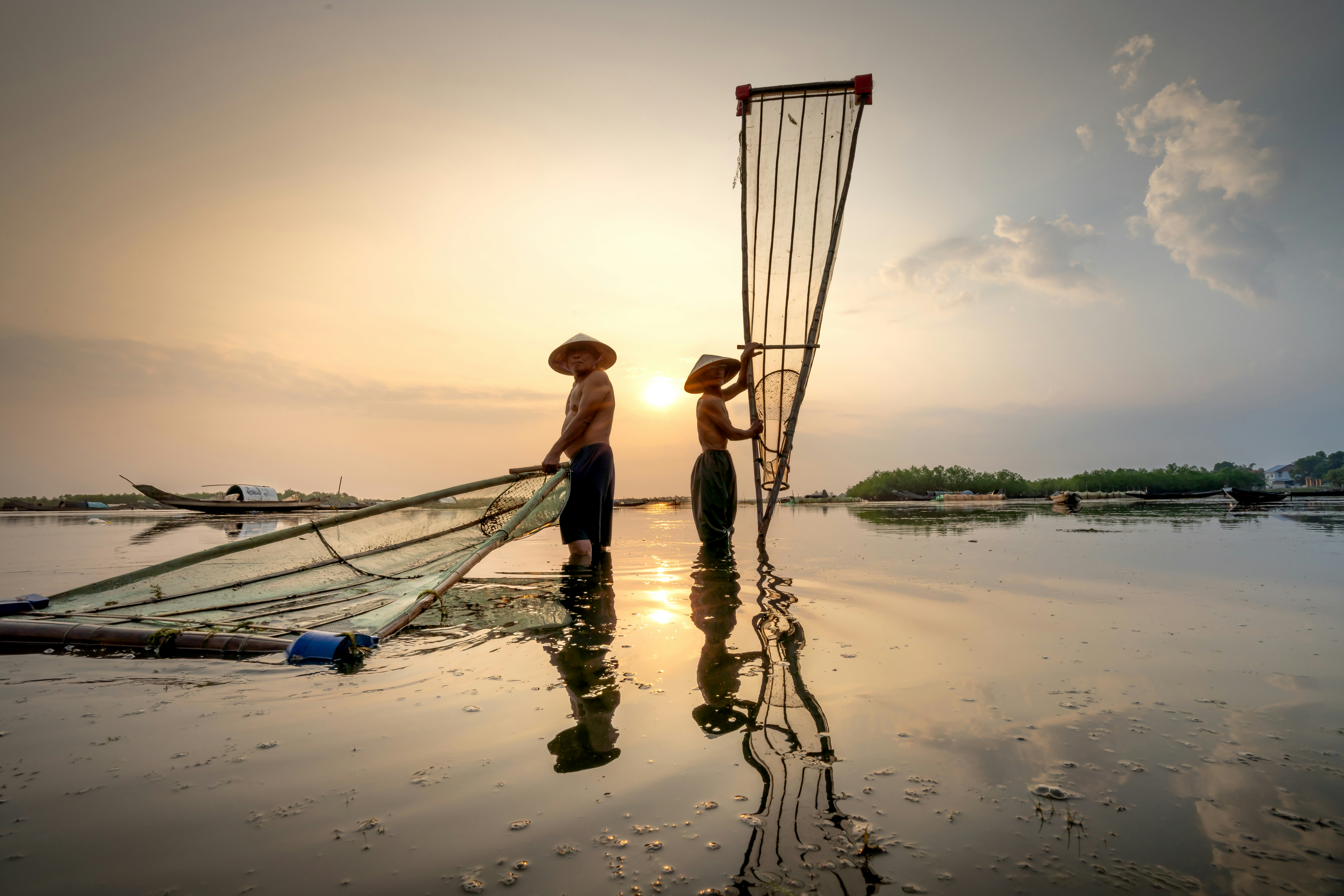 Couple of people standing next to a boat on a body of water
