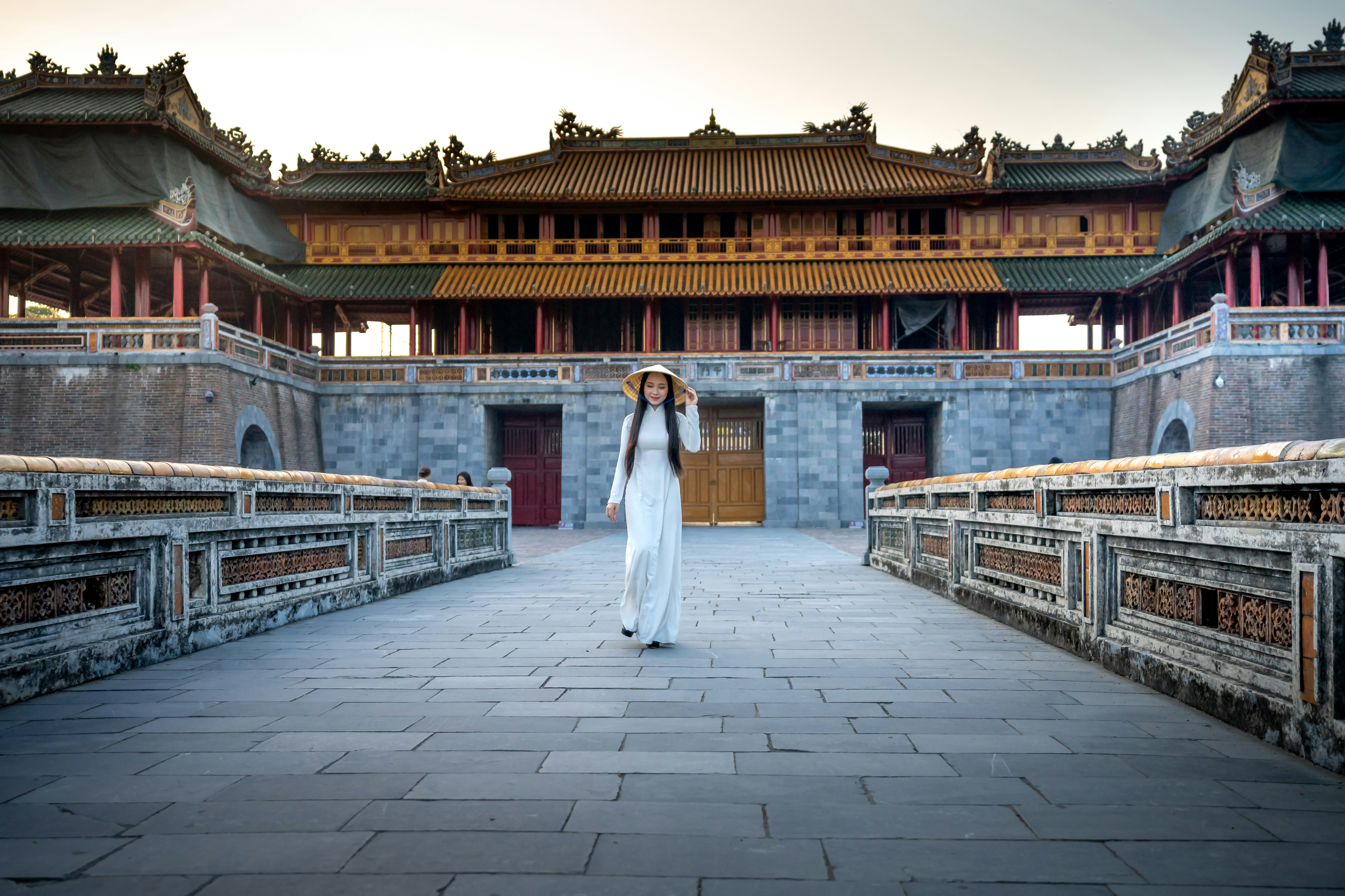 a woman in a white dress standing in a courtyard