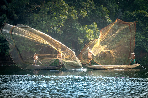 three people on small boats with fishing nets