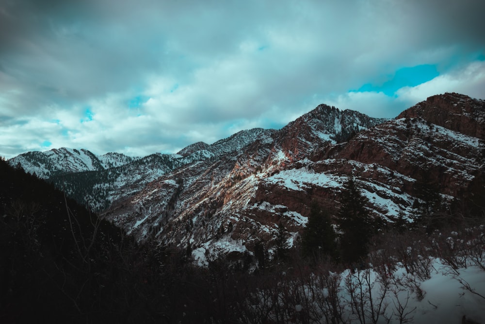 a snowy mountain range under a cloudy sky