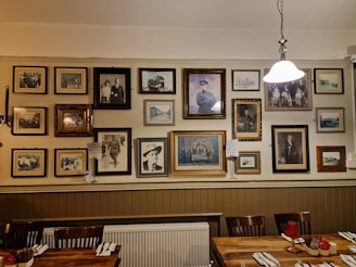 A stylish dining room wall featuring a mix of vintage and contemporary framed art hung with expert craftsmanship.