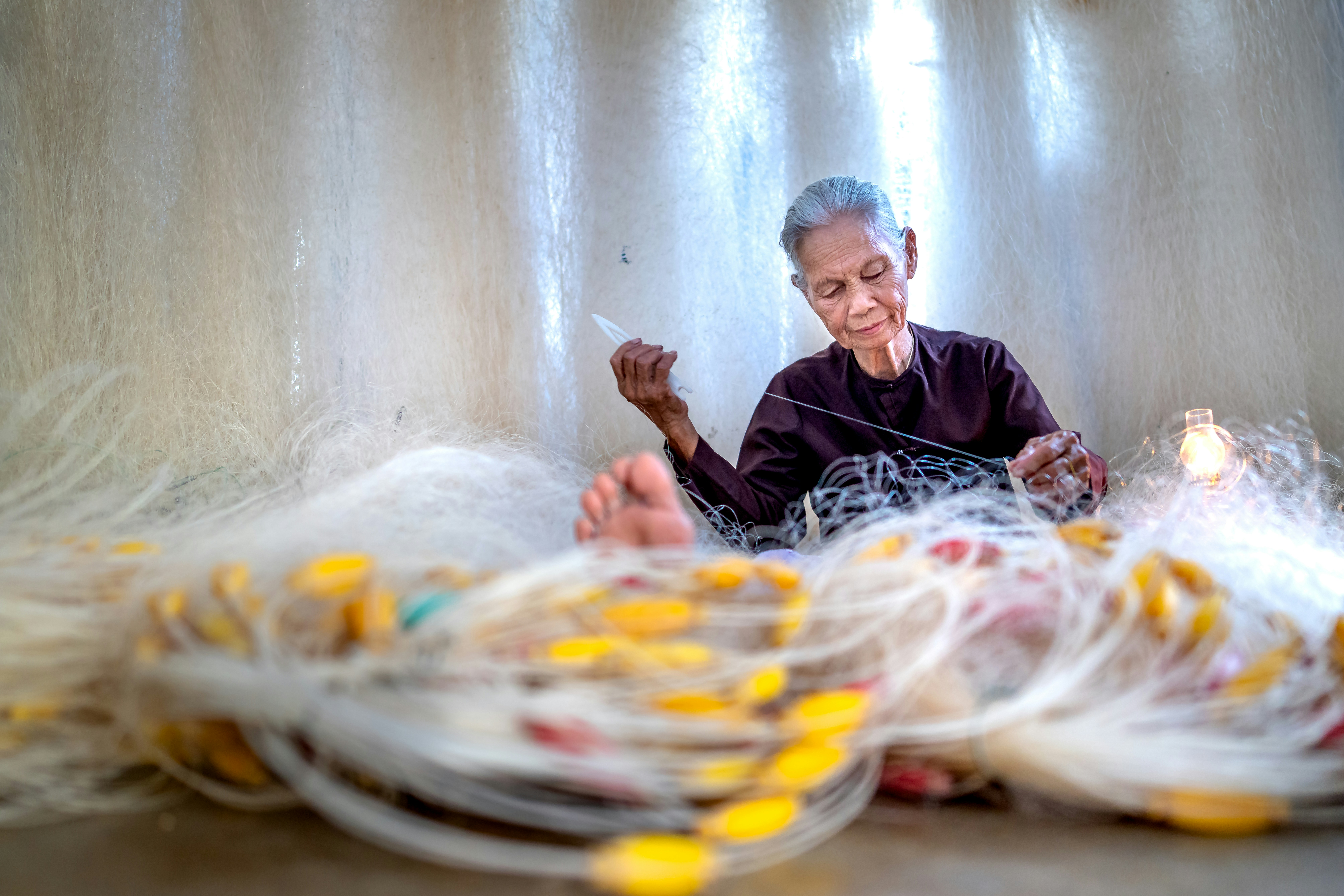 a woman sitting in front of a pile of yarn