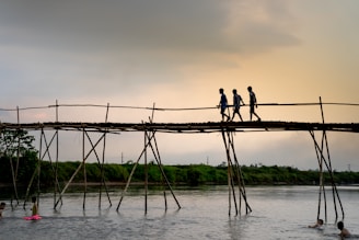 The kids crossing a wooden bridge over a bubbling mountain stream during a morning hike.