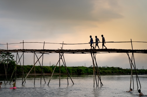 The kids crossing a wooden bridge over a bubbling mountain stream during a morning hike.