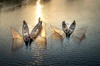 Traditional Goan fishermen casting nets at sunrise along the coastline.