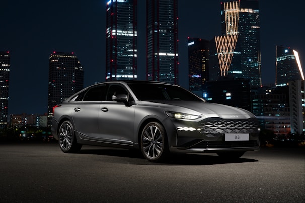 a silver car parked in front of a city at night