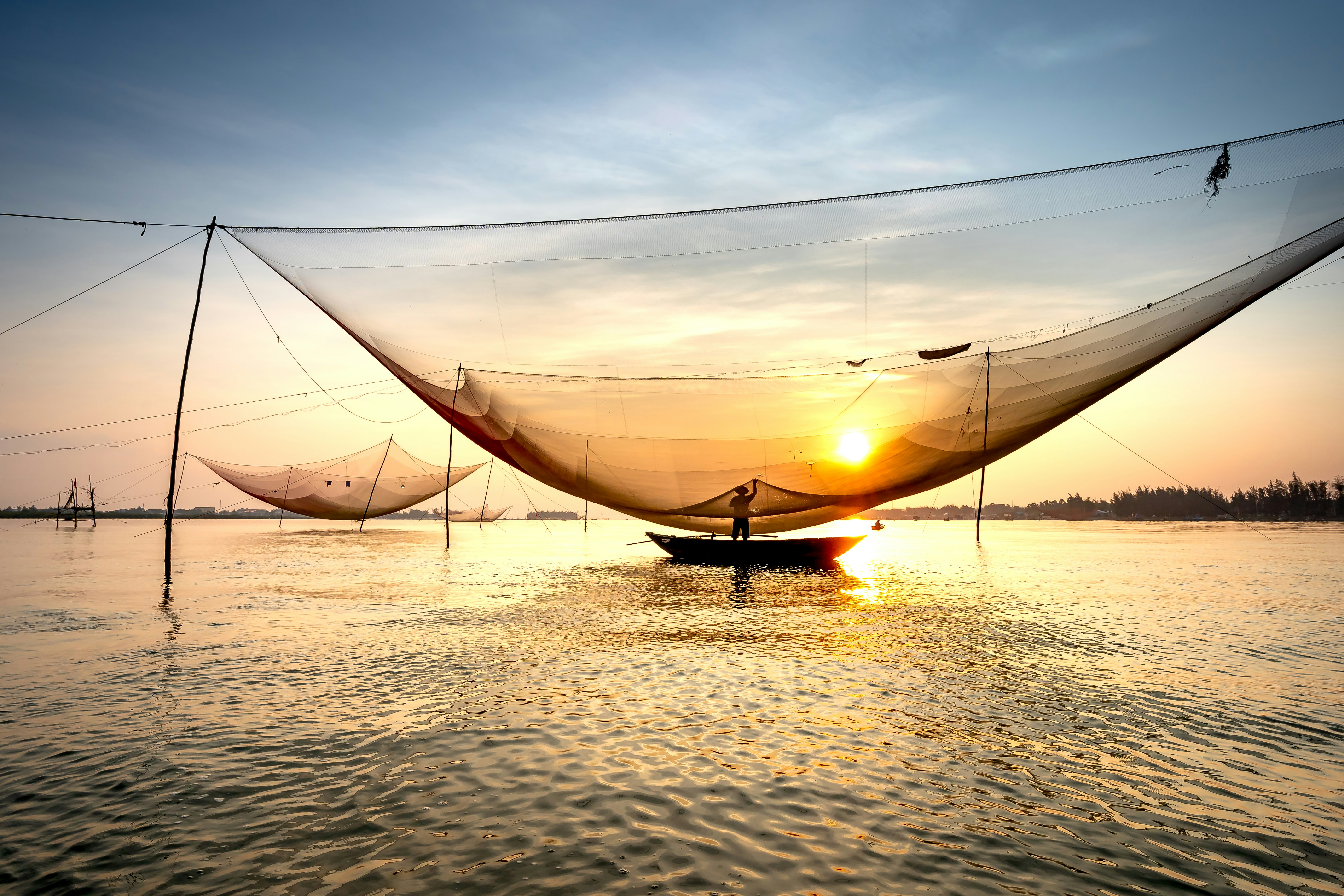 a fishing net in the water at sunset