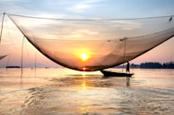 A serene scene of a fisherman setting his nets on a calm Balinese lagoon at dawn.