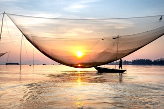 A serene scene of a fisherman setting his nets on a calm Balinese lagoon at dawn.