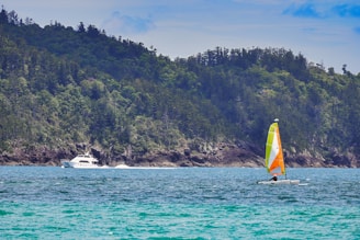 A vibrant boat sailing near Pulau Songsong with clear blue waters and lush greenery in the background.