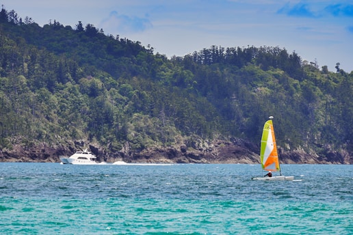 A vibrant boat sailing near Pulau Songsong with clear blue waters and lush greenery in the background.