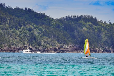 A vibrant boat sailing near Komodo Island with clear blue waters and lush green hills in the background