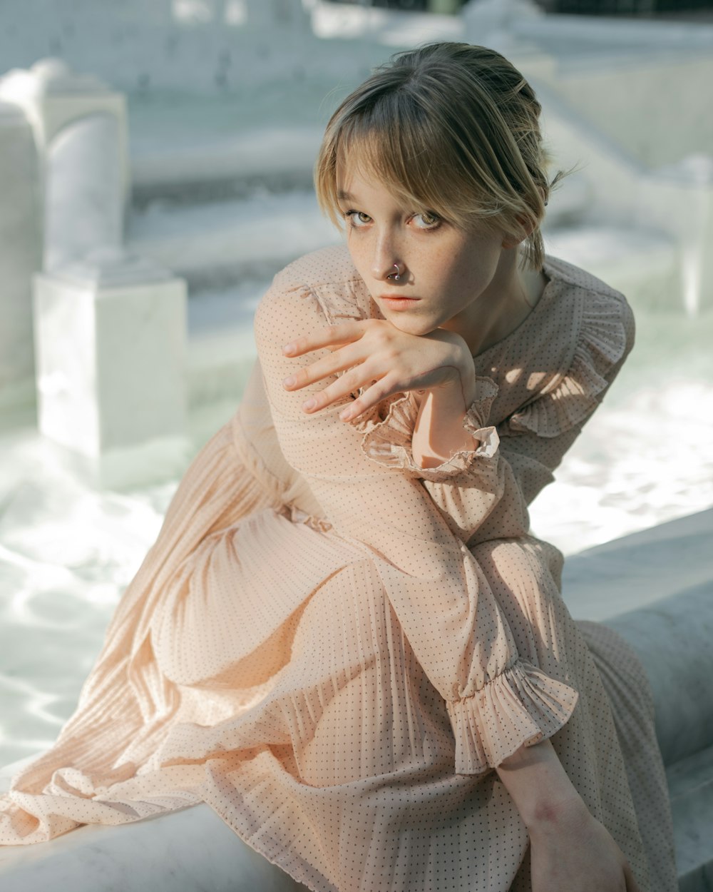 a woman in a pink dress sitting on a ledge