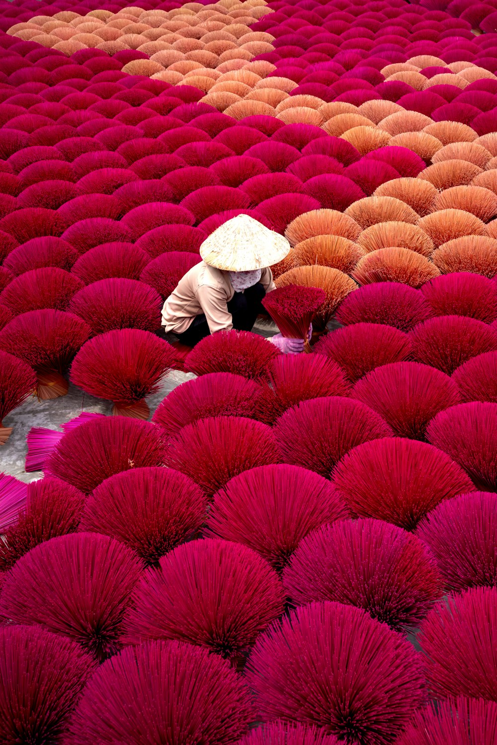 a person kneeling down in a field of red and orange umbrellas