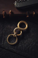 A sleek matte forest green belt coiled neatly beside a vintage leather crafting tool on parchment.
