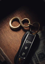 Close-up of a cash stack and car keys on a sleek black surface.