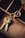 A close-up view of a set of keys attached to a unique keyring with an intertwined double ring design. The keys and keyring are placed on the edge of a wooden compartmentalized organizer, with different sections visible and a piece of torn paper partially seen in the upper right corner.