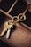 A close-up view of a set of keys attached to a unique keyring with an intertwined double ring design. The keys and keyring are placed on the edge of a wooden compartmentalized organizer, with different sections visible and a piece of torn paper partially seen in the upper right corner.
