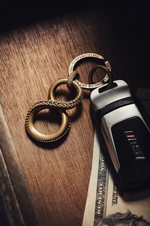 Close-up of a delicate minimalist silver keychain resting on a wooden table.