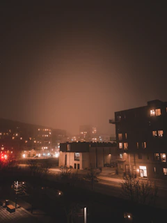 A wide cinematic shot of Brooklyn streets at night, empty except for subtle fog and the faint glow of distant streetlights.