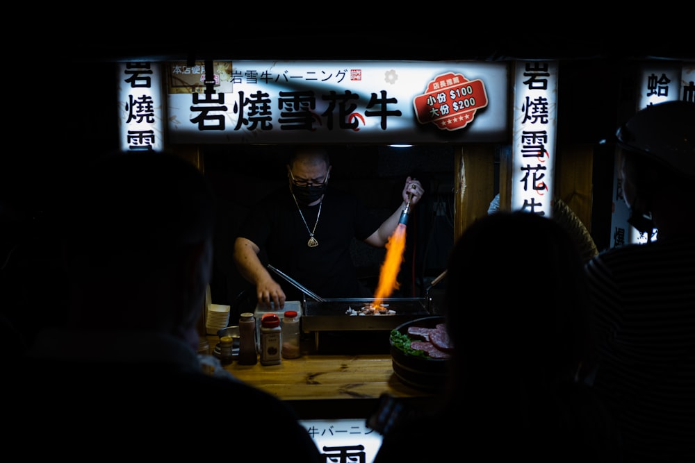 a group of people standing around a table with food